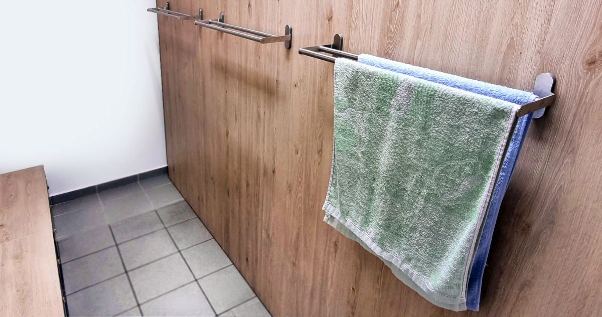 Krycí stěna kovových šatních skříněk se sušáky na ručníky.