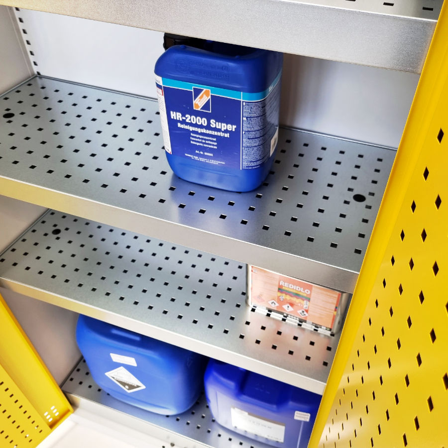 Vnitřní prostor skladové skříně pro uložení chemikálií se speciálními zádržnými policemi.